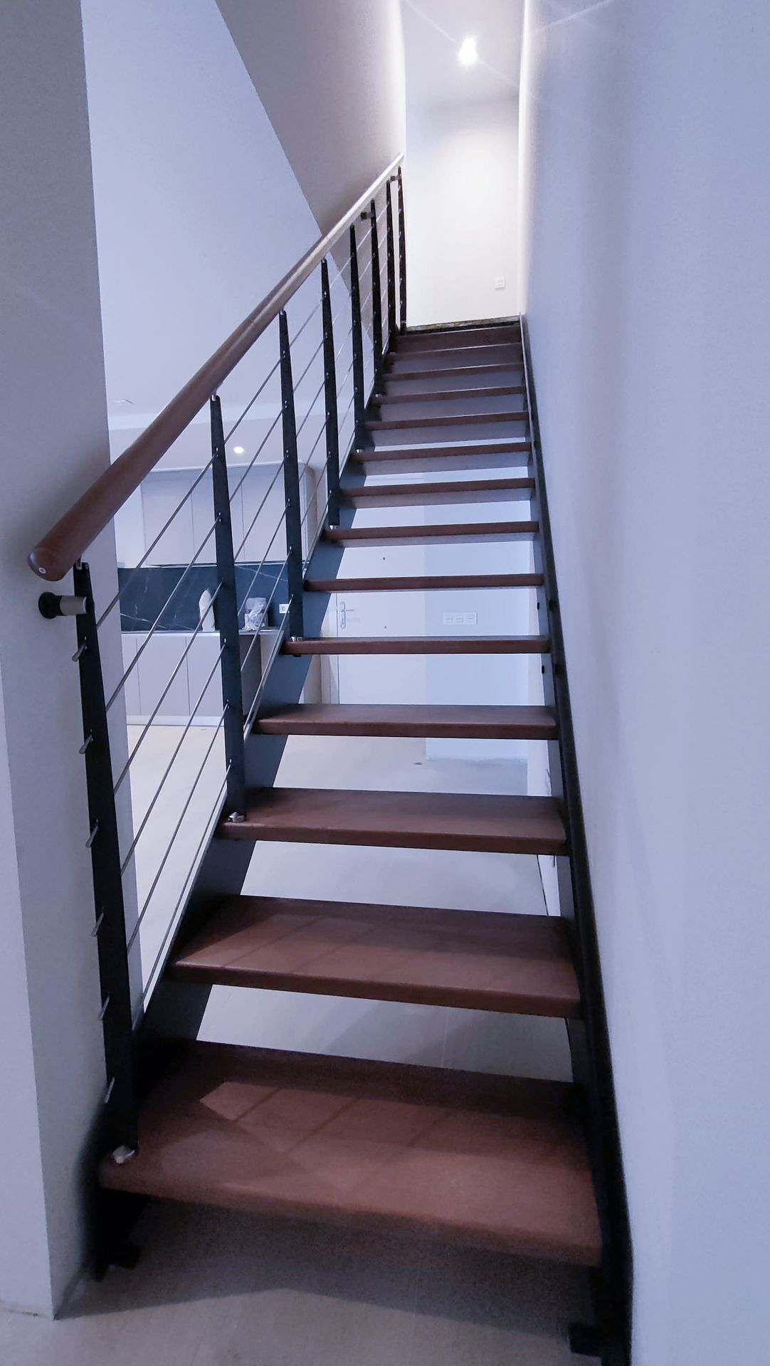 Escalera interior con barandilla metálica y pasamanos de madera