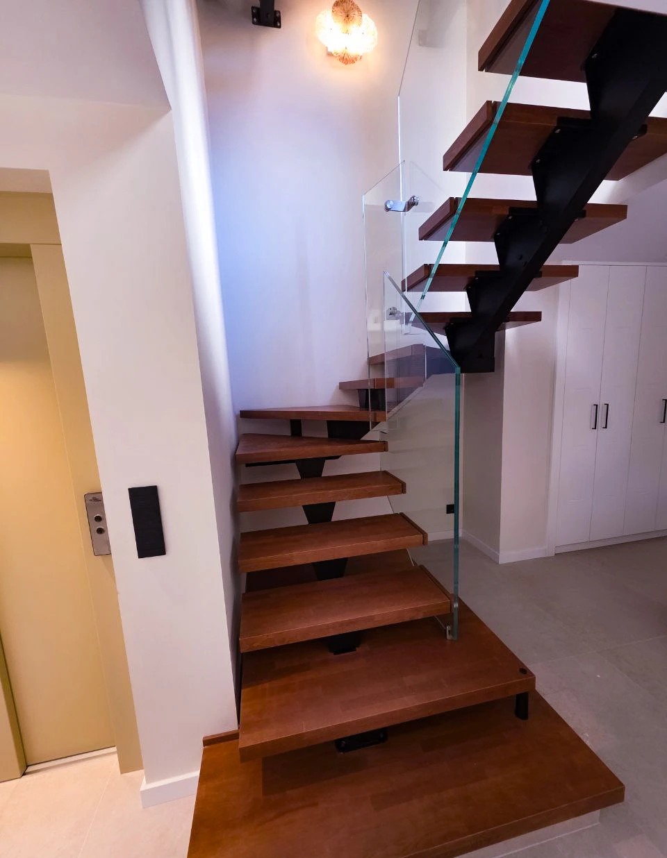 Escalera metálica flotante con peldaños de madera y barandilla de cristal en vivienda moderna en Barcelona