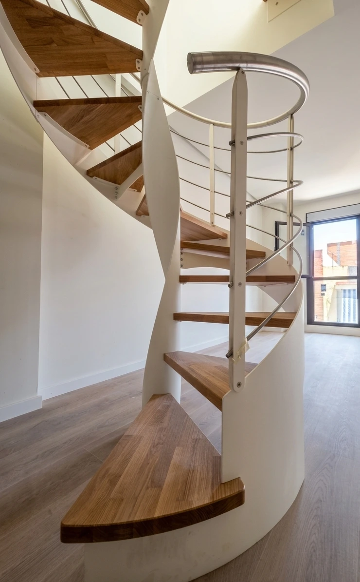 Detalle de escalera helicoidal de acero y madera en proyecto residencial de Sevilla