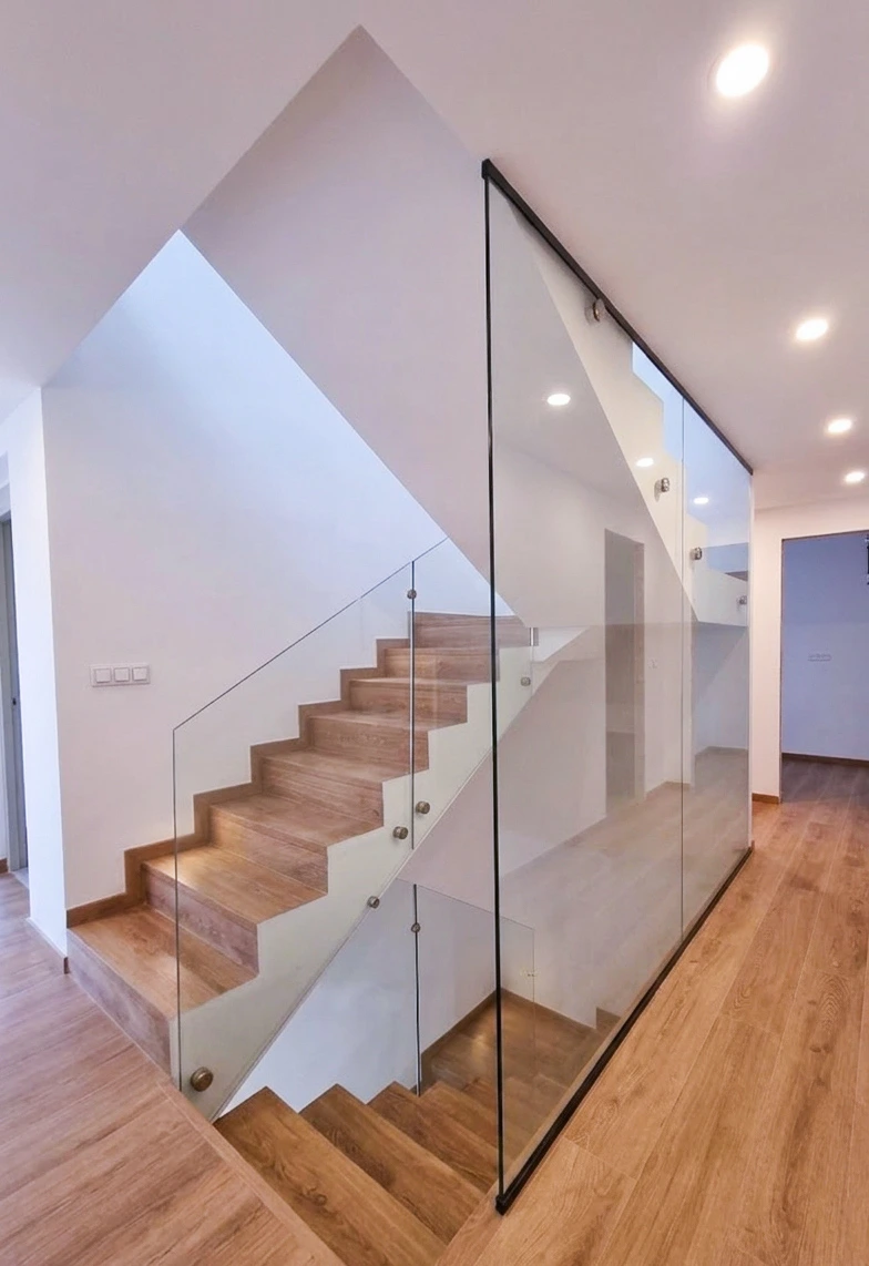 detalle de barandilla de cristal en escalera con botones de acero inoxidable